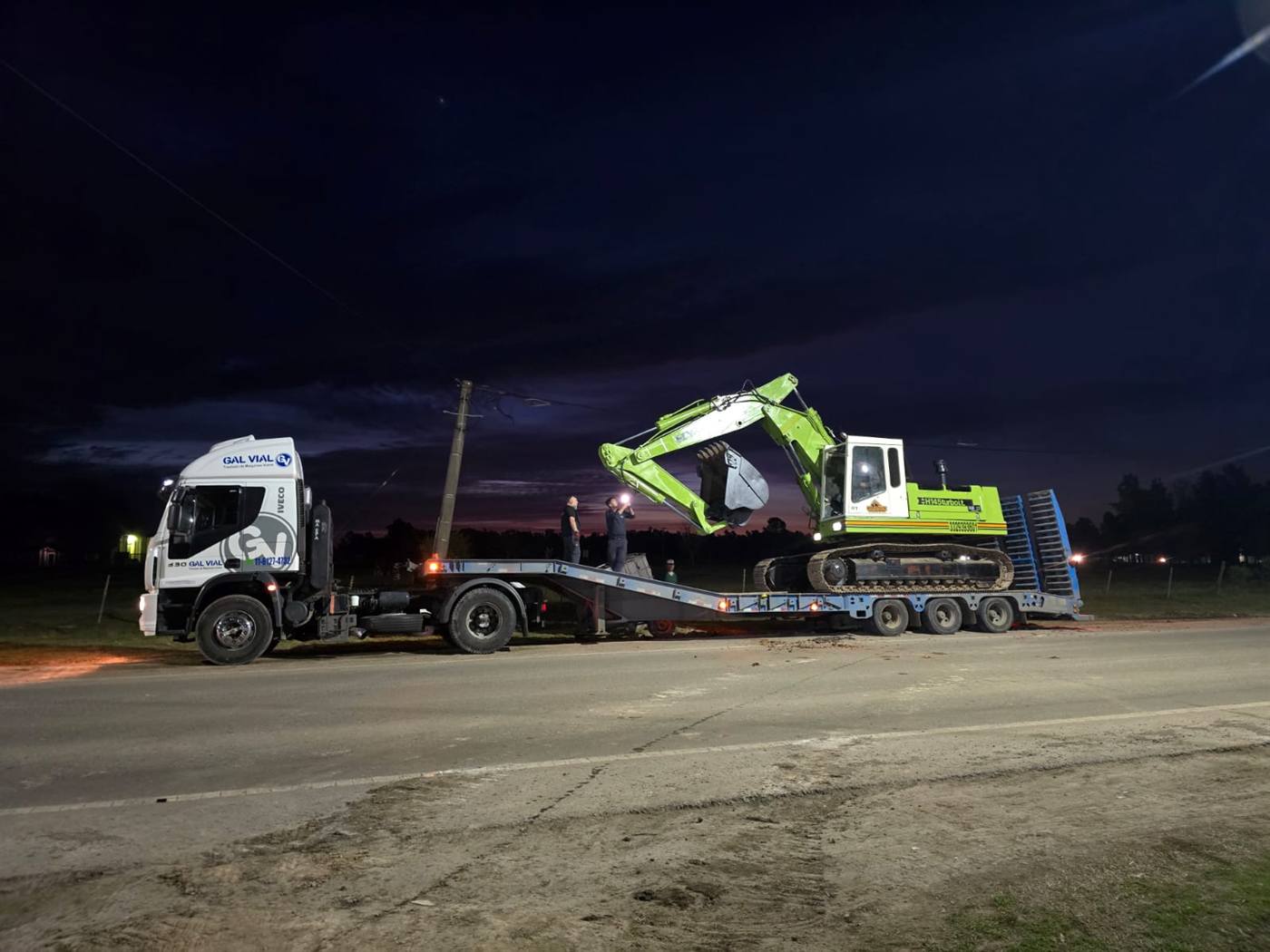 Camión con carretón de Hidra Dock trasladando una excavadora de noche
